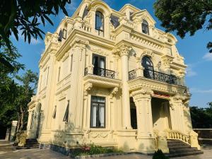 Un grand bâtiment blanc avec des escaliers se trouve juste devant. dans l'établissement Đinh Gia Home Villa & Resort, à Ninh Binh