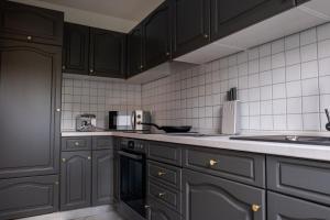 a kitchen with black cabinets and white tiles at Klassen Apartments! Zentral und bequem, entdecken Sie Bad Schussenried in Bad Schussenried