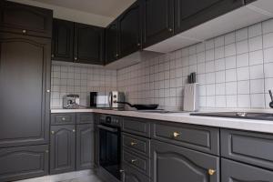 kuchnia z czarnymi szafkami i białymi płytkami w obiekcie Klassen Apartments! Zentral und bequem, entdecken Sie Bad Schussenried w mieście Bad Schussenried