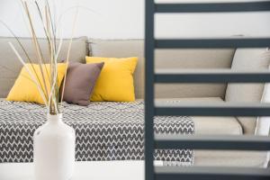 a white vase on a table next to a bed with pillows at Lemon Tree Houses in Áno Meriá