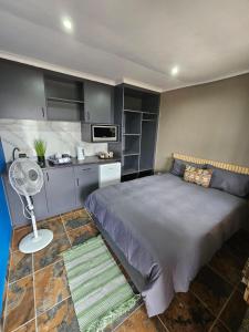 a small bedroom with a bed and a kitchen at SavannaSkies Stays in Hillcrest
