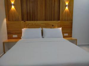 - un lit avec 2 oreillers blancs dans l'établissement FUNDUQ AL BUSYRA, à Pantai Cenang