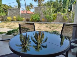 une table en verre avec un palmier au-dessus dans l'établissement FUNDUQ AL BUSYRA, à Pantai Cenang