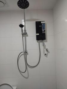 a shower in a bathroom with a phone on the wall at FUNDUQ AL BUSYRA in Pantai Cenang