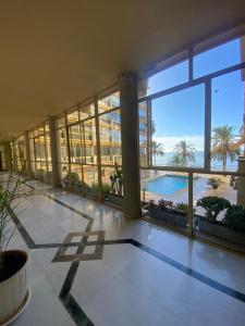 a large building with a view of a pool and palm trees at Marbella Edificio Mayoral primera línea de playa y centro ciudad in Marbella