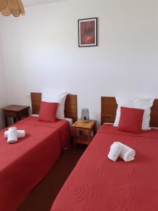 two beds in a room with red sheets at Résidence Les Clarines ( by Popinns ) in Les Rousses
