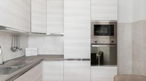 a kitchen with white cabinets and a microwave at Piazza Alboreto 72 - Rozzano in Rozzano
