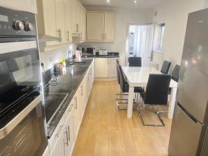 a kitchen with white cabinets and a table with chairs at Lovely 5 Bed house in Medway sleeps 12 in Gillingham