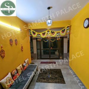 Hotel SAMARTH PALACE في ماهاباليشوار: غرفة بجدار اصفر وساعة على الحائط