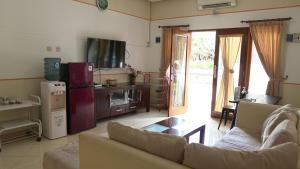 ein Wohnzimmer mit einem Sofa und einem TV sowie eine Küche in der Unterkunft Adiputra Guesthouse Tata Bumi in Ngabean