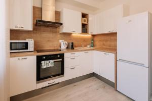a white kitchen with white cabinets and a refrigerator at SKAU 1 Old Town Family & Business Apartment 1floor Free parking in Bratislava