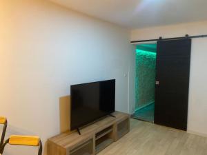 sala de estar con TV de pantalla plana y puerta en Petite maison plain-pied climatisé, en Migné-Auxances