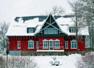 une maison rouge recouverte de neige dans l'établissement Villa Silva - Oberhof - Nebenhaus Berghotel Oberhof - nur Übernachtung, à Oberhof