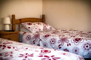 a bedroom with two beds with red and white sheets at RB Contractor Stays - Celyn in Pwllheli