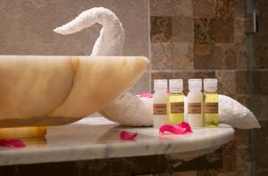 bañera con botellas de aceites esenciales junto a un fregadero en Riad Marana Hotel & Spa, en Marrakech