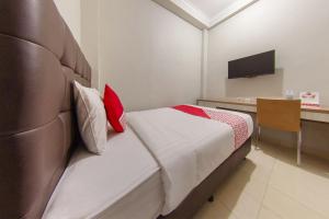 una camera d'albergo con letto e scrivania di OYO 657 Elite Residence Central Park Mall By TOS a Giacarta
