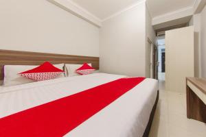 ein rotes und weißes Bett in einem weißen Zimmer in der Unterkunft OYO 657 Elite Residence Central Park Mall By TOS in Jakarta