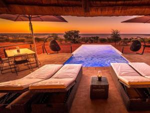 a swimming pool with a table and an umbrella at Bagatelle Kalahari Boutique Farmhouse Lodge in Mariental