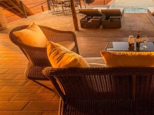a patio with two wicker chairs and a table with wine glasses at Bagatelle Kalahari Boutique Farmhouse Lodge in Mariental