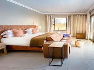 um quarto com uma cama grande e um sofá em Bagatelle Kalahari Boutique Farmhouse Lodge em Mariental