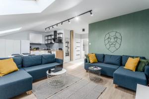 a living room with blue couches and a kitchen at Chill Apartments Warszawa Piaseczno in Józefosław