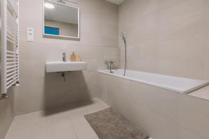 La salle de bains blanche est pourvue d'un lavabo et d'une baignoire. dans l'établissement SKAU Coral Residence in Sky Park 22 floor 1Tower Panoramic View Free Parking, à Bratislava