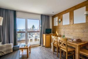 a living room with a wooden table and a dining room at Résidence Pierre & Vacances Le Pédrou in Font-Romeu