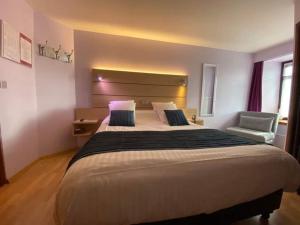 - une chambre avec un grand lit et une chaise dans l'établissement Hotel Beau Site, à Francorchamps