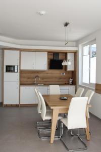 a kitchen with a wooden table and white chairs at Apartment Simona in Kranjska Gora