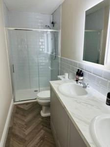 e bagno con servizi igienici, lavandino e doccia. di Brand New Riverside Apartment a Christchurch