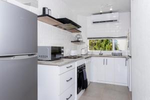 a white kitchen with white cabinets and a microwave at Beautiful Chaka's Cove apartment in Ballito
