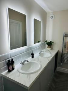 a bathroom with two sinks and two mirrors at Brand New Riverside Apartment in Christchurch