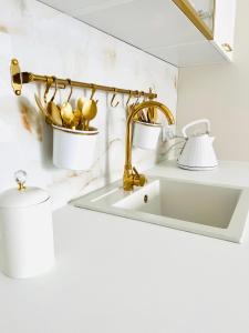 a bathroom sink with a gold faucet and a lamp at LuxApart Apartamenty Jantar in Jantar