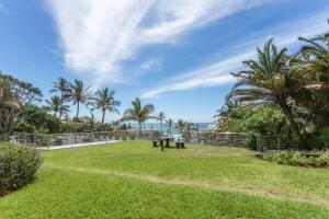 a park with palm trees and grass and a fence at Beautiful Chaka's Cove apartment in Ballito