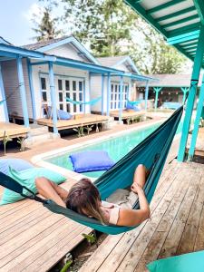 a woman laying in a hammock next to a pool at Casa Kapuas in Gili Trawangan