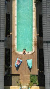 un hombre tendido en una balsa al lado de una piscina en Casa Kapuas, en Gili Trawangan
