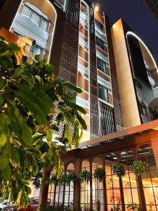 un edificio alto con árboles delante de él en SO Zen Hotel Silom Bangkok en Bang Rak