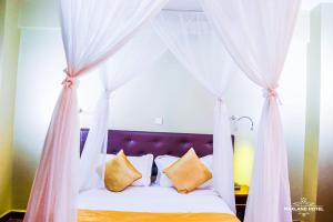Maxland Hotel في نيروبي: غرفة نوم مع سرير المظلة مع الوسائد الصفراء