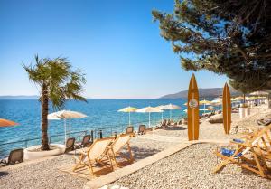 einen Strand mit Liegestühlen und Sonnenschirmen und dem Meer in der Unterkunft Valamar Sanfior Hotel & Casa in Rabac