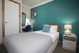 a bedroom with a bed and a blue wall at Temple View Hotel in Carinish