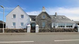 a large white house with a stone wall at Temple View Hotel in Carinish