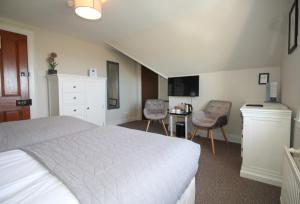a bedroom with a bed and two chairs and a desk at Temple View Hotel in Carinish
