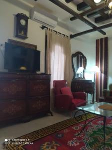 uma sala de estar com televisão e uma cómoda com relógio em Dar El Bey em Tozeur