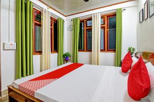 um quarto com uma cama com cortinas verdes e almofadas vermelhas em OYO Flagship Narangam Homestay em Darjeeling
