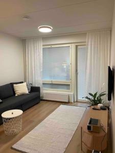 a living room with a black couch and a window at Bronx - Apartment in Vantaa