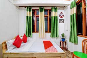 um quarto com uma cama com cortinas vermelhas e verdes em OYO Flagship Narangam Homestay em Darjeeling