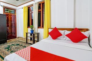 um quarto com uma cama com almofadas vermelhas e uma televisão em OYO Flagship Narangam Homestay em Darjeeling