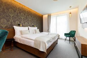 a hotel room with a large bed and a green chair at Hotel Historia Malomkert in Veszprém