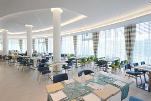 - une salle à manger avec des tables, des chaises et des fenêtres dans l'établissement Isola di Albarella Hotel Capo Nord, à Albarella