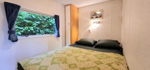 Schlafzimmer mit einem Bett und einem Fenster in der Unterkunft Stacaravan in de natuur bij Maastricht in Ulestraten